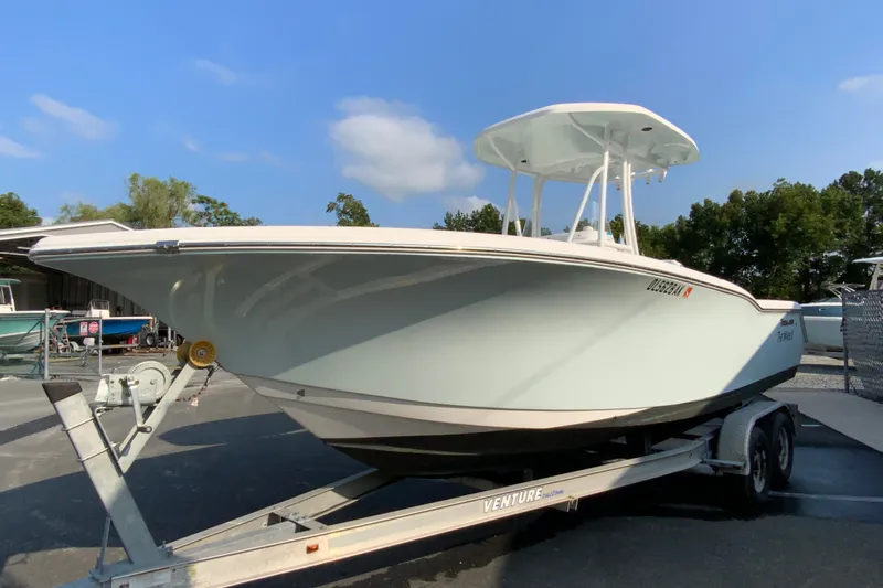 Slide: The Image of 2015 Tidewater 230 CC Adventure boat on trailer, parked outdoors under clear blue sky. - 5
