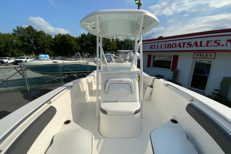 Slide: The Image of 2015 Tidewater 230 CC Adventure boat at dealership, featuring spacious deck and seating. - 23