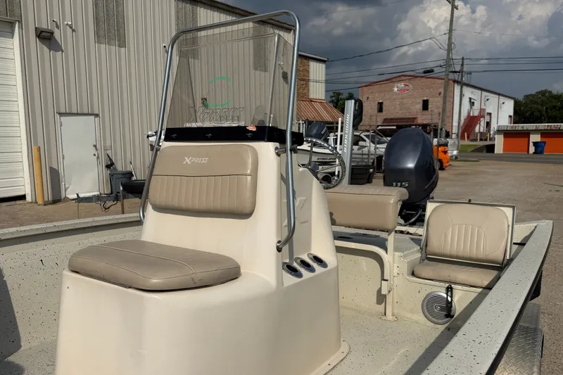 Slide: The Image of 2013 Xpress H20B Bay boat with seating, parked outdoors near industrial buildings. - 18