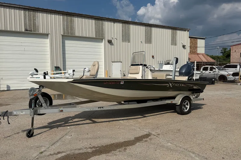 The Image of 2013 Xpress H20B Bay boat on trailer, parked outside industrial building. - 1