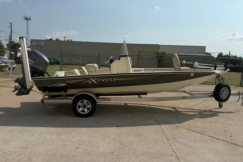 Slide: The Image of 2013 Xpress H20B Bay boat on trailer, parked outdoors, featuring Yamaha outboard motor. - 6