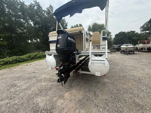 Slide: The Image of A 2002 Harris Sunliner 220 pontoon boat with a Suzuki outboard motor, parked on a gravel lot. - 7