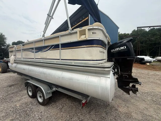 Slide: The Image of A 2002 Harris Sunliner 220 pontoon boat on a trailer. It features a Suzuki outboard motor. - 5