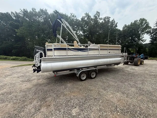 The Image of A 2002 Harris Sunliner 220 pontoon boat on a trailer in a gravel lot. - 1