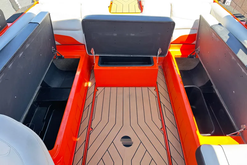 Slide: The Image of 2018 Malibu Wakesetter 22 MXZ interior storage compartments, open, with orange and black accents. - 20