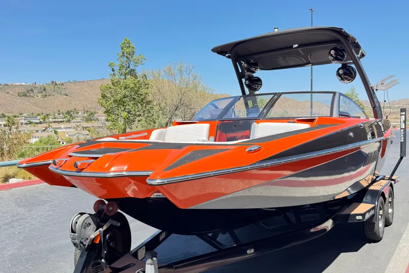 Slide: The Image of 2018 Malibu Wakesetter 22 MXZ boat with vibrant orange and black design on a trailer. - 3