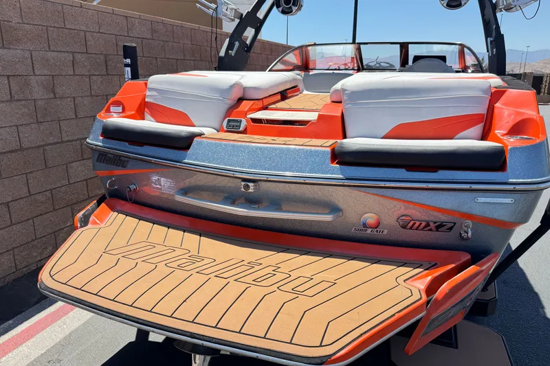 Slide: The Image of 2018 Malibu Wakesetter 22 MXZ boat with orange accents and cushioned seating. - 6