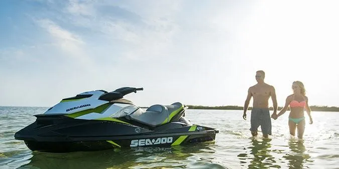 Slide: The Image of A 2017 Sea-Doo GTI SE 130 sits in shallow water. A couple holds hands nearby. - 3