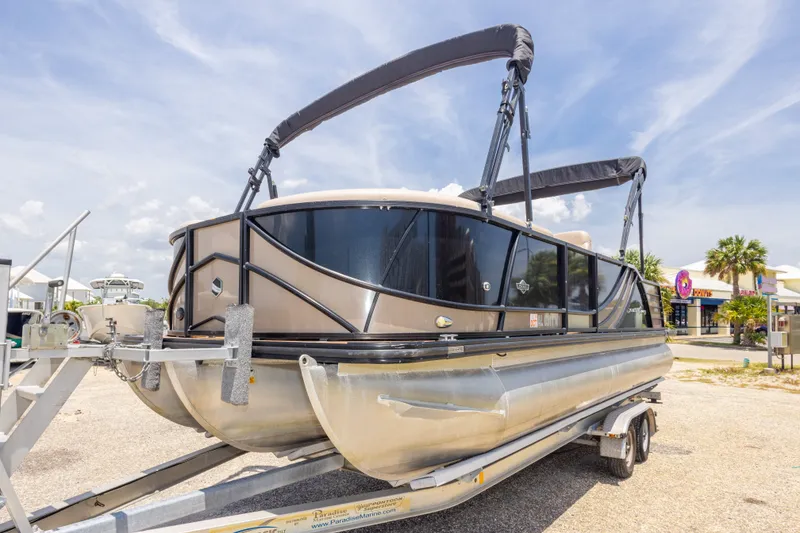 Slide: The Image of 2017 South Bay 523SL pontoon boat on trailer, sunny day, palm trees in background. - 11