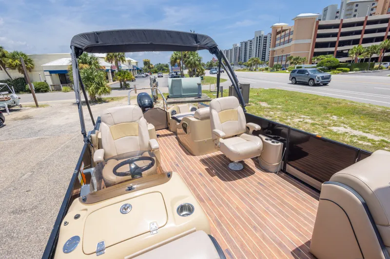 Slide: The Image of 2017 South Bay 523SL pontoon boat with beige seating, parked near a road and buildings. - 28
