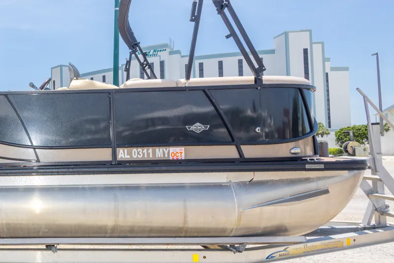 Slide: The Image of 2017 South Bay 523SL pontoon boat on trailer, parked near a modern building. - 41