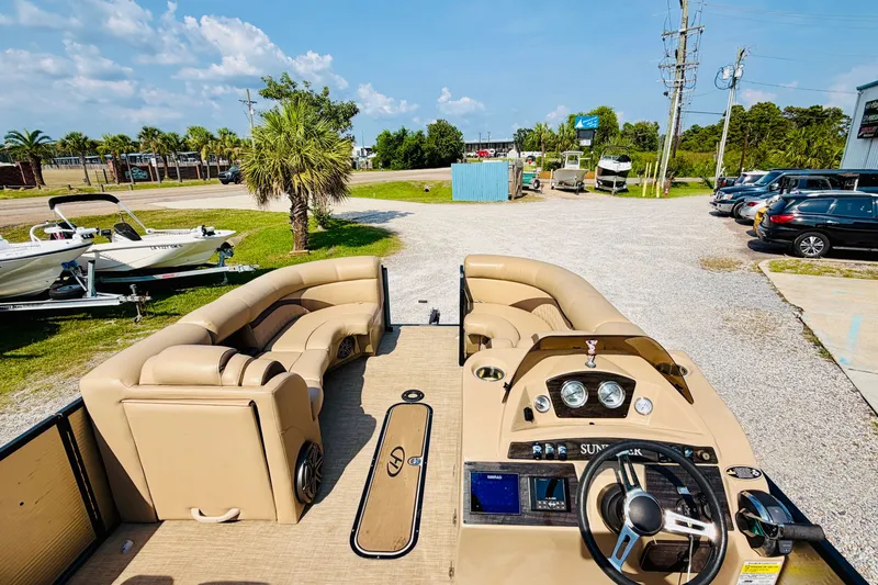 Slide: The Image of 2019 Harris Sunliner 230 pontoon boat with beige seating, parked outdoors on a sunny day. - 23