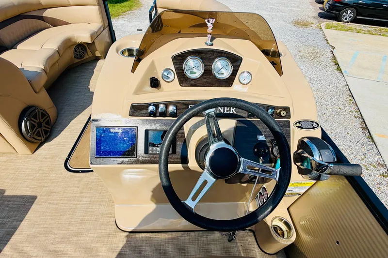 Slide: The Image of 2019 Harris Sunliner 230 boat dashboard with steering wheel and navigation controls. - 18