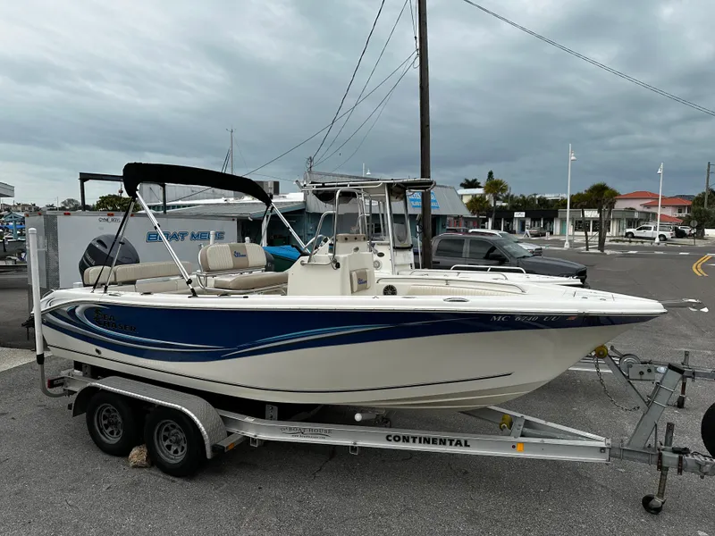 Slide: The Image of A 2016 Sea Chaser 20 HFC on a trailer, featuring blue accents and a Bimini top. - 15