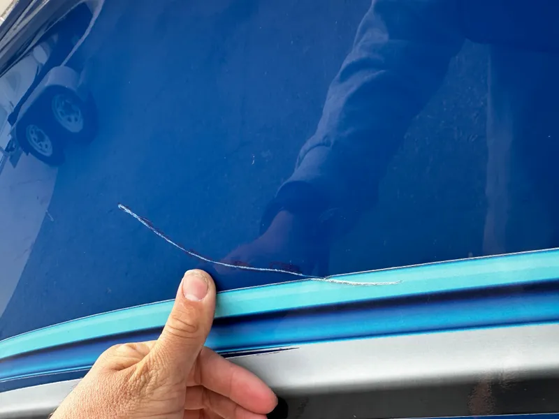 Slide: The Image of Close-up of a blue boat hull with a long scratch. A hand points to the damage. - 9