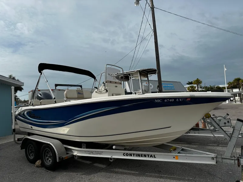 The Image of A 2016 Sea Chaser 20 HFC boat on a trailer, featuring blue accents and a Bimini top. - 0