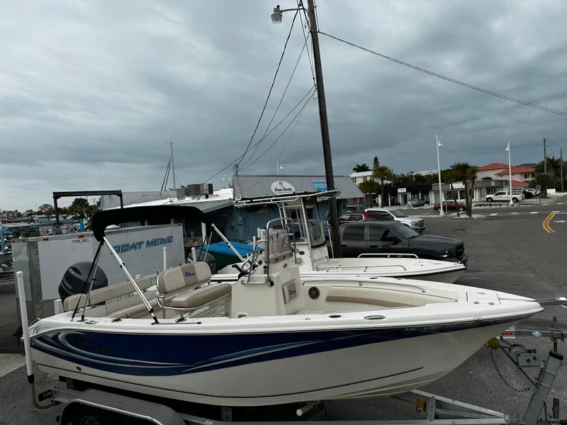 Slide: The Image of A white boat with blue accents sits on a trailer under a cloudy sky. - 17