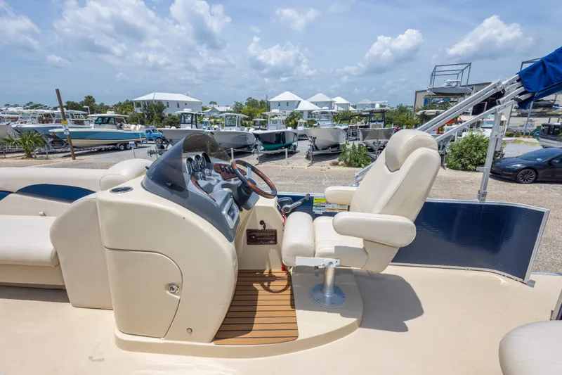 Slide: The Image of 2014 Aqua Patio 22 SLC boat interior with captain's chair and control panel, docked at marina. - 20
