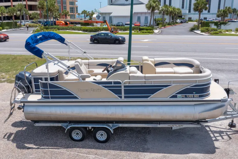 Slide: The Image of 2014 Aqua Patio 22 SLC pontoon boat on trailer, parked near a road. - 2