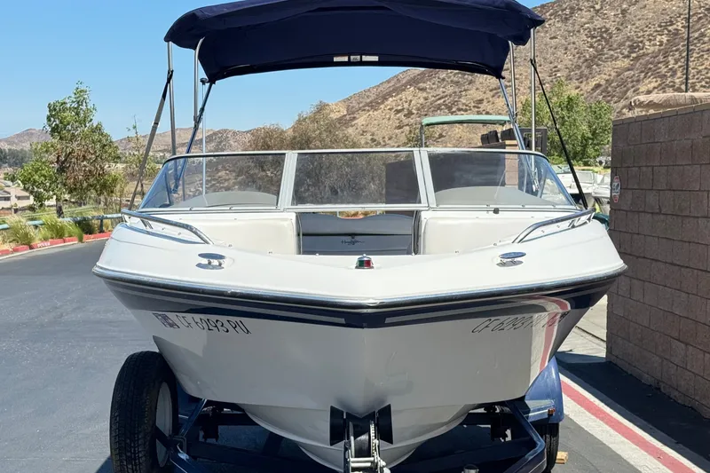 Slide: The Image of 2001 Four Winns 180 Horizon boat with canopy on trailer, parked outdoors. - 2