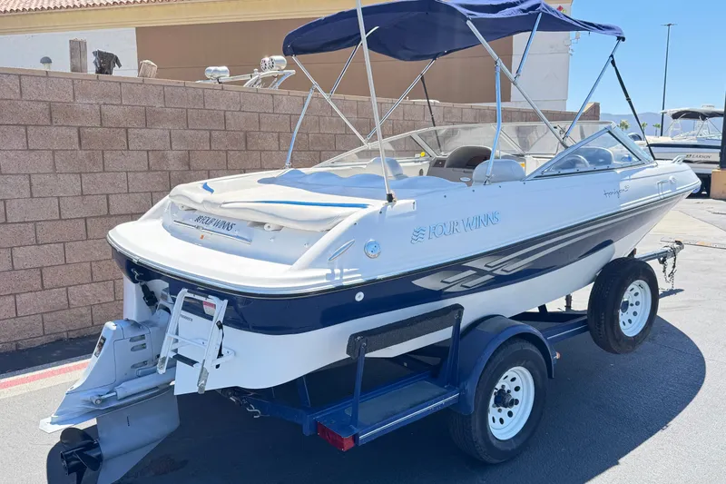 Slide: The Image of 2001 Four Winns 180 Horizon boat on trailer, featuring a blue and white design. - 5