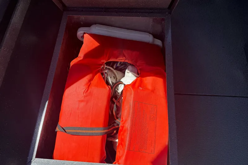 Slide: The Image of Orange life jacket stored in a compartment of a 2000 North River 18 Mariner boat. - 17