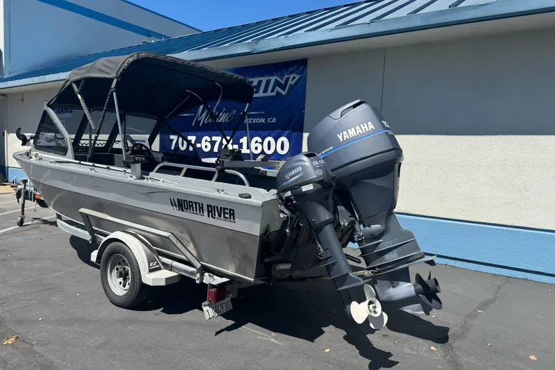 Slide: The Image of 2000 North River 18 Mariner boat with Yamaha outboard motors, parked outside a marine shop. - 11