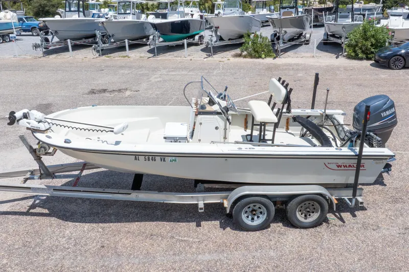 Slide: The Image of 1986 Boston Whaler 18 Outrage boat on trailer, parked in a marina with other boats. - 3