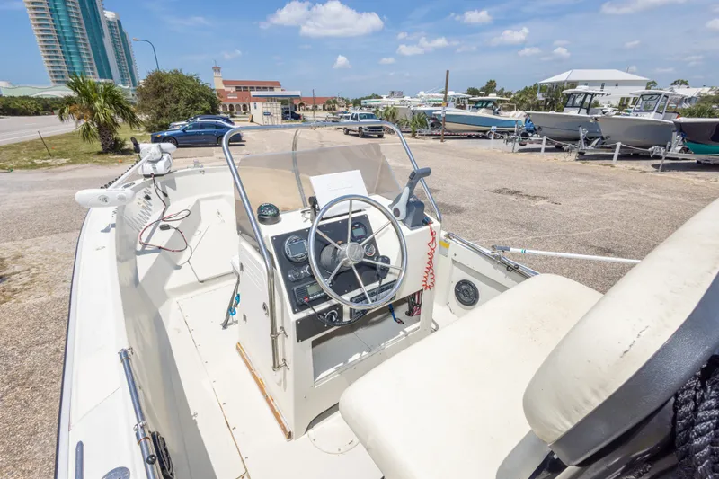 Slide: The Image of 1986 Boston Whaler 18 Outrage boat interior with steering wheel and controls, parked outdoors. - 24