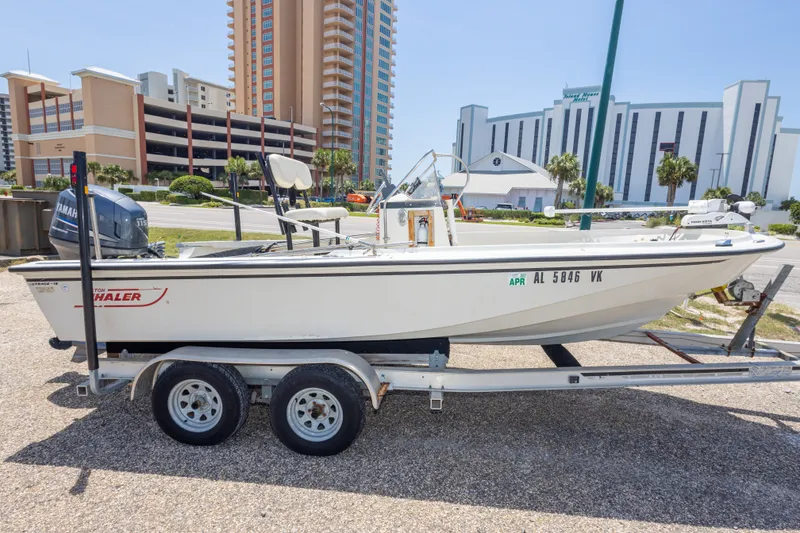 Slide: The Image of 1986 Boston Whaler 18 Outrage boat on trailer, parked near tall buildings. - 10