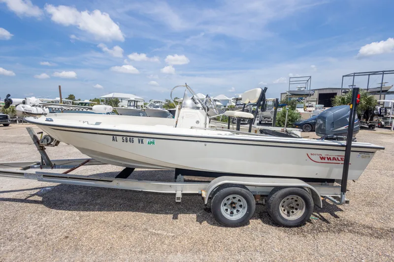Slide: The Image of 1986 Boston Whaler 18 Outrage boat on trailer under a clear blue sky. - 14