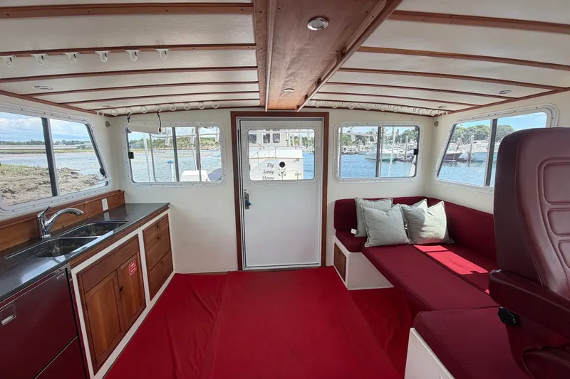 Slide: The Image of Interior of 2016 Young Brothers Downeast boat with red seating, wooden cabinetry, and waterfront view. - 13