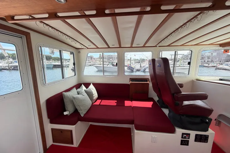 Slide: The Image of Interior of 2016 Young Brothers Downeast boat with red seating and harbor view. - 21
