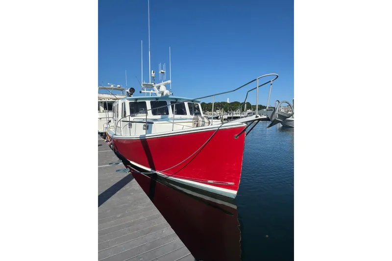 The Image of Red 2016 Young Brothers Downeast boat docked in a marina under clear blue sky. - 2