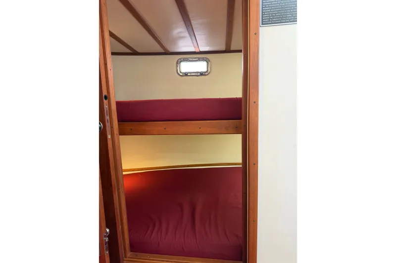 Slide: The Image of Bunk beds in 2016 Young Brothers Downeast boat cabin with wooden frame and red bedding. - 30
