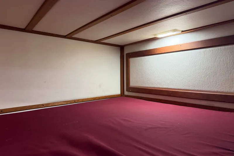 Slide: The Image of Interior cabin of 2016 Young Brothers Downeast boat with red bedding and wooden trim. - 29