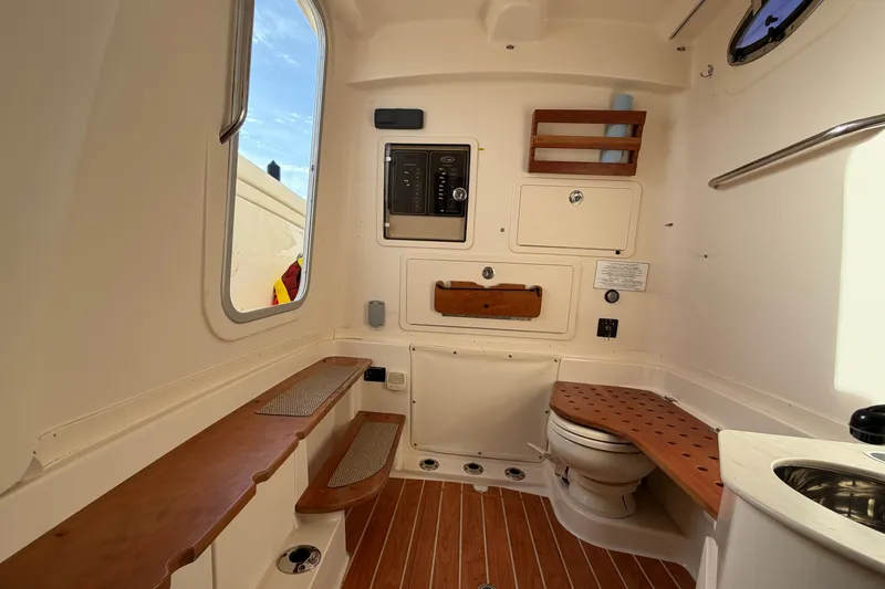 Slide: The Image of Interior of 2019 Grady-White Canyon 336 boat, featuring a compact bathroom with wooden accents. - 46