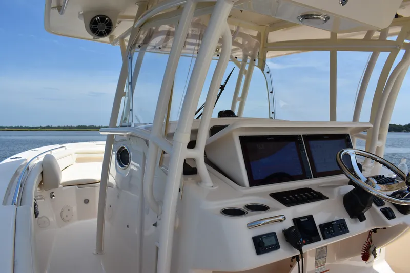 Slide: The Image of 2019 Grady-White Canyon 336 boat cockpit with dual screens and steering wheel, overlooking water. - 36