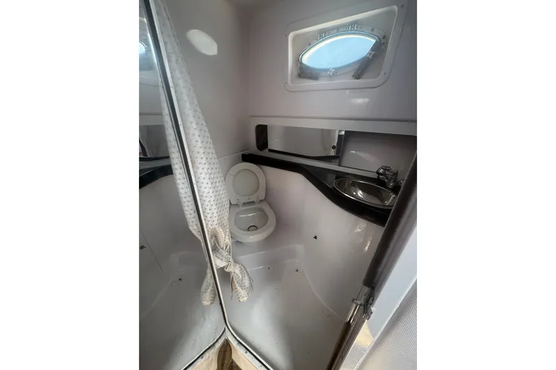 The Image of 2003 PROLINE 33 Express boat bathroom with toilet, sink, and porthole window. - 1