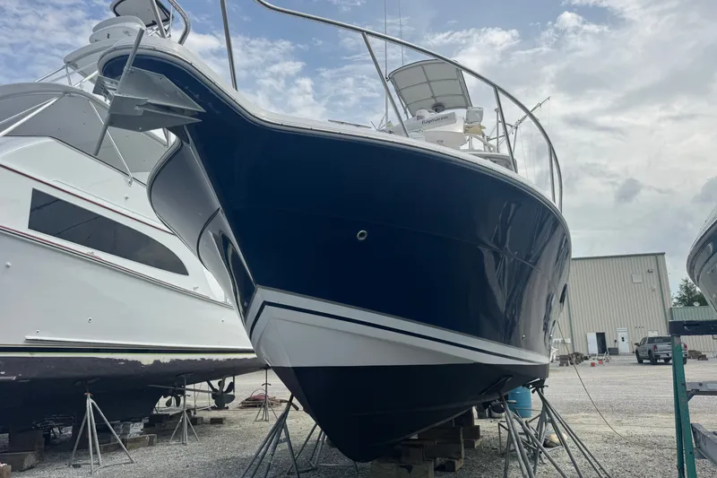 Slide: The Image of 2003 PROLINE 33 Express boat on dry dock, blue hull, overcast sky. - 41