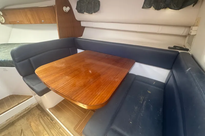 Slide: The Image of 2003 PROLINE 33 Express cabin interior with wooden table and blue seating. - 3
