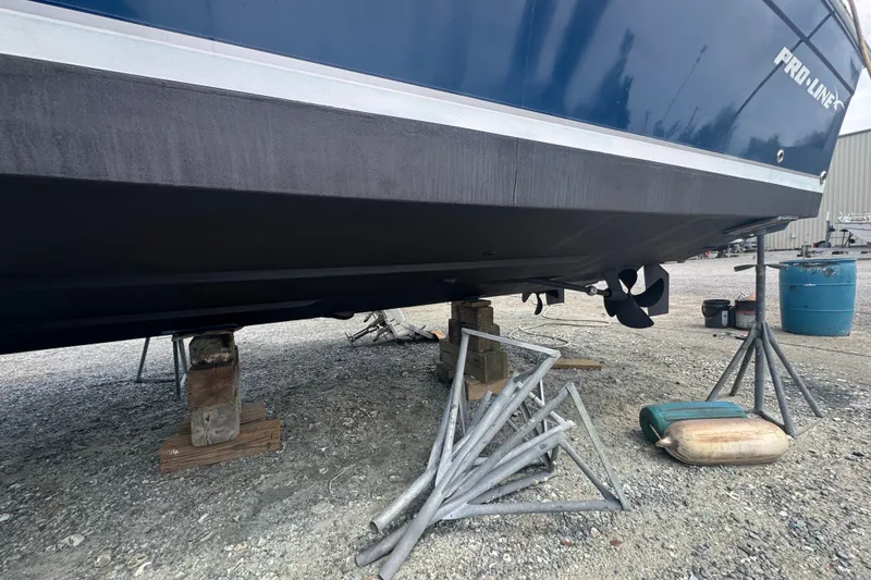 Slide: The Image of 2003 PROLINE 33 Express boat on stands, showing hull and propeller in a boatyard. - 43