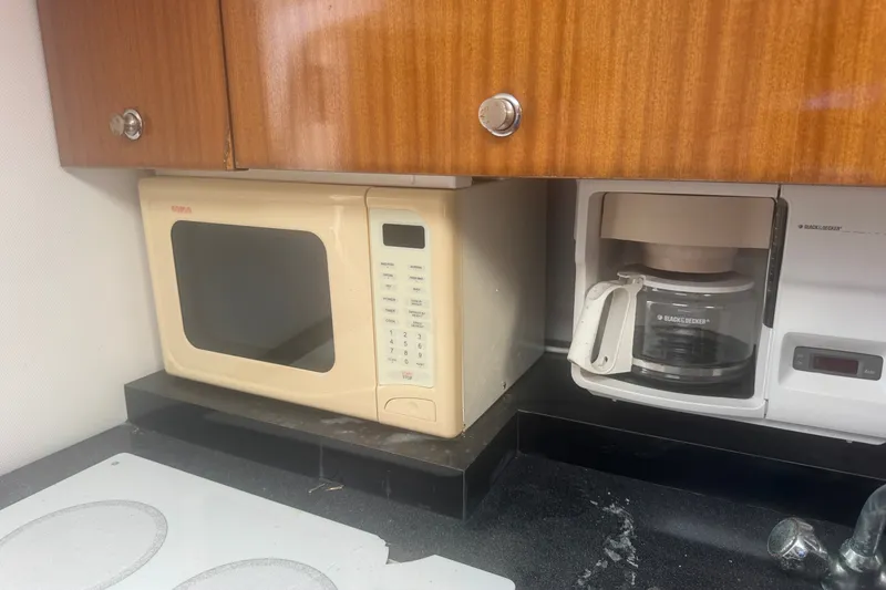 Slide: The Image of Kitchen appliances on a 2003 PROLINE 33 Express boat, featuring a microwave and coffee maker. - 5