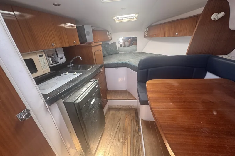 Slide: The Image of 2003 PROLINE 33 Express cabin interior with kitchenette, seating, and sleeping area. - 2