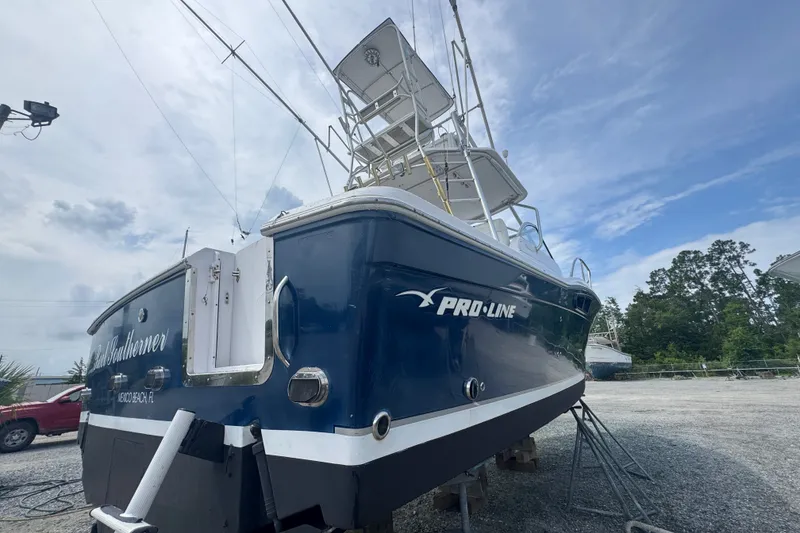 Slide: The Image of 2003 PROLINE 33 Express boat on dry dock, blue hull, clear sky background. - 47