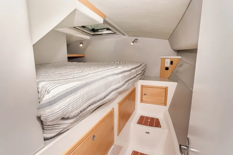 Slide: The Image of Cozy cabin interior of 2021 ArrowCat 320 with bed and storage compartments. - 25