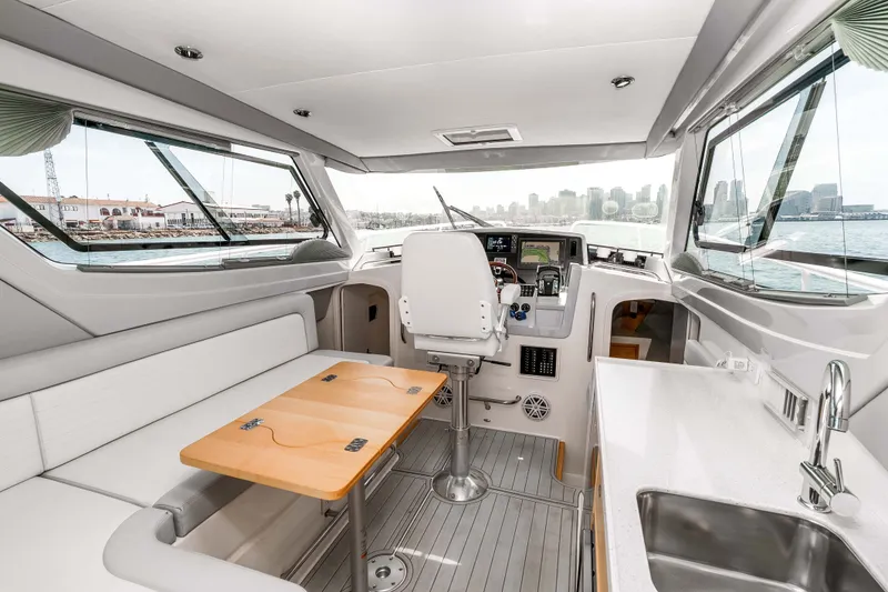Slide: The Image of Interior of 2021 ArrowCat 320 boat with helm, seating, and kitchenette overlooking waterfront. - 17