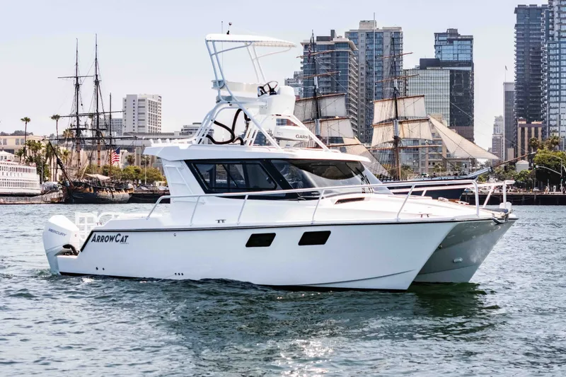 Slide: The Image of 2021 ArrowCat 320 boat cruising in urban harbor with city skyline backdrop. - 2