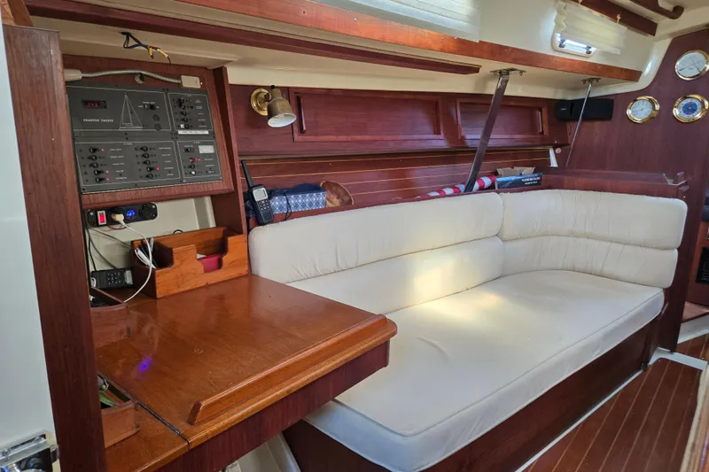 Slide: The Image of Interior of a 1990 Pearson 385 sailboat with a cozy seating area and navigation panel. - 11