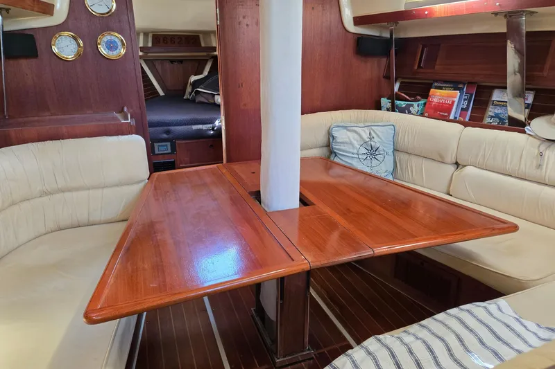 Slide: The Image of Interior of a 1990 Pearson 385 sailboat with wooden table and cushioned seating. - 9